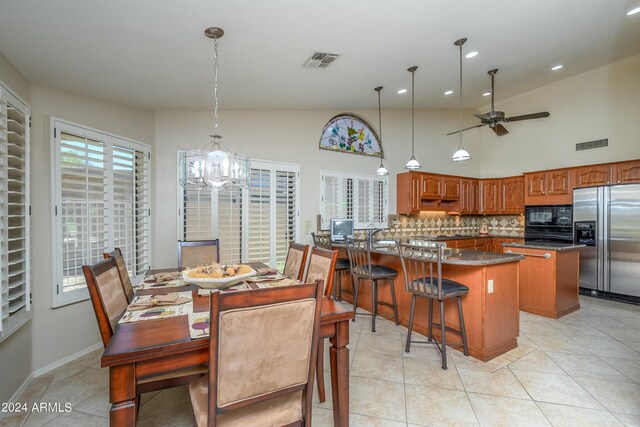 dining area featuring ceiling fan with notable chandelier, vaulted ceiling, and light tile patterned floors