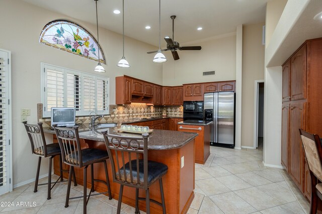 kitchen with stainless steel refrigerator with ice dispenser, pendant lighting, a kitchen bar, kitchen peninsula, and ceiling fan