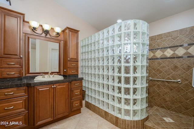 bathroom with vanity, a tile shower, and tile patterned flooring