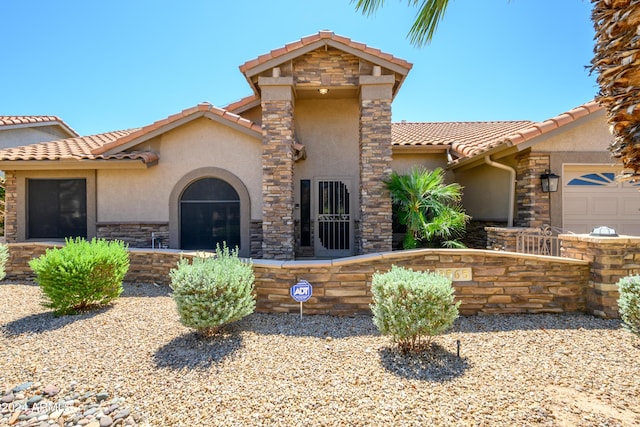 mediterranean / spanish-style home featuring a tiled roof, stone siding, and stucco siding