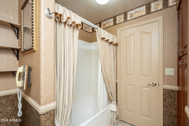 bathroom with a textured ceiling and shower / bathtub combination with curtain