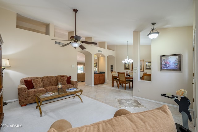 tiled living room featuring lofted ceiling and ceiling fan with notable chandelier