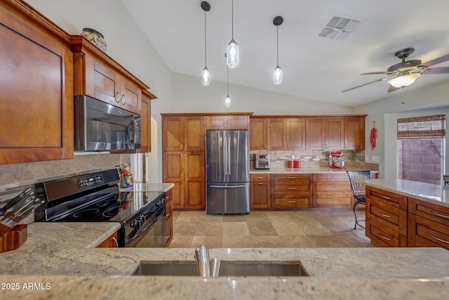 kitchen featuring pendant lighting, sink, stainless steel refrigerator, light stone counters, and black range with electric cooktop