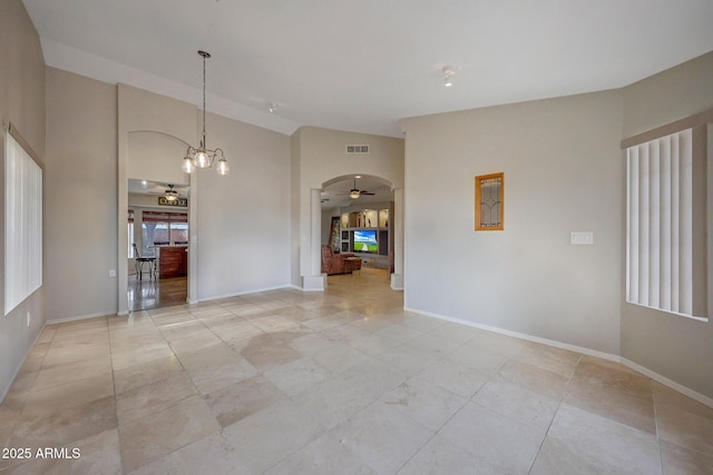 unfurnished room with ceiling fan with notable chandelier and high vaulted ceiling