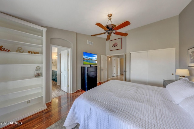 bedroom featuring ceiling fan, wood-type flooring, ensuite bathroom, and a closet