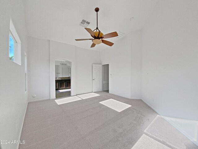 unfurnished room with ceiling fan, high vaulted ceiling, and light colored carpet