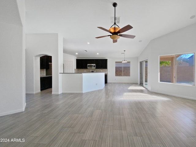 unfurnished living room with light hardwood / wood-style floors, ceiling fan, and vaulted ceiling