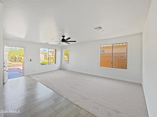 carpeted spare room with a textured ceiling and ceiling fan