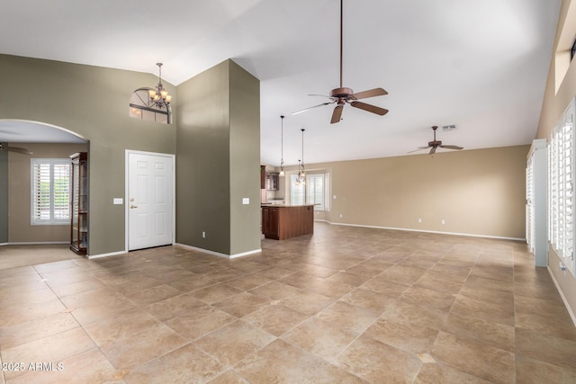 unfurnished living room with arched walkways, high vaulted ceiling, ceiling fan with notable chandelier, visible vents, and baseboards