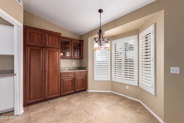 kitchen with lofted ceiling, baseboards, glass insert cabinets, and hanging light fixtures