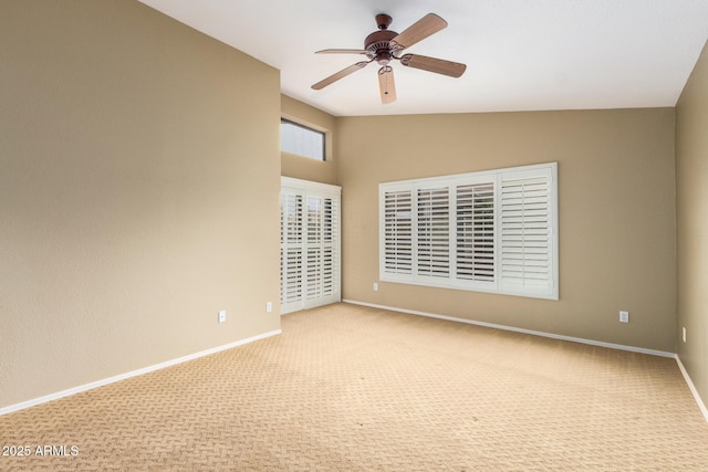 carpeted spare room with a ceiling fan, vaulted ceiling, and baseboards