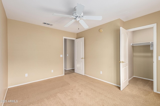 unfurnished bedroom featuring a closet, light colored carpet, visible vents, a spacious closet, and baseboards