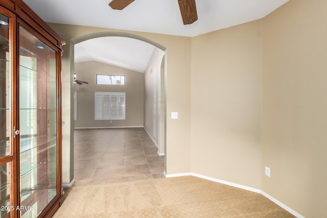 hallway featuring arched walkways, light carpet, lofted ceiling, and baseboards