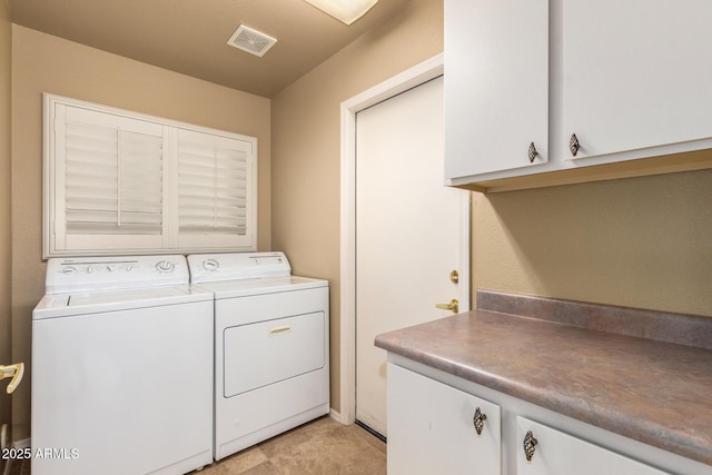 washroom with visible vents, cabinet space, and washing machine and clothes dryer