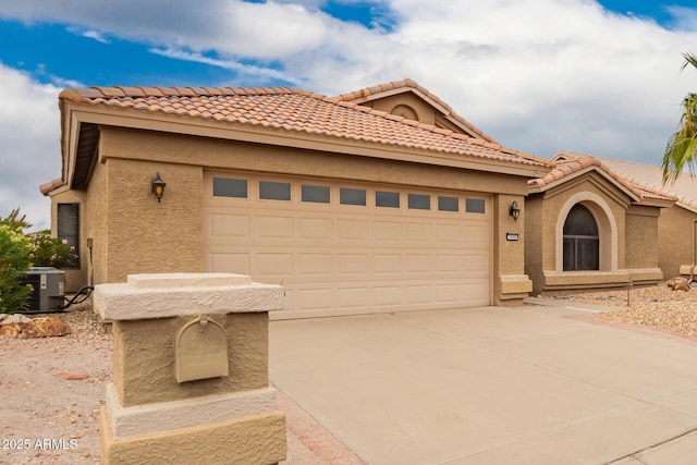 mediterranean / spanish-style home featuring an attached garage, driveway, cooling unit, and stucco siding