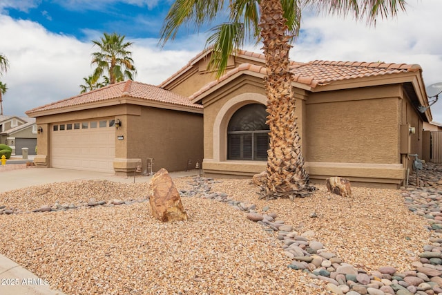 view of front facade with a garage, concrete driveway, a tile roof, and stucco siding