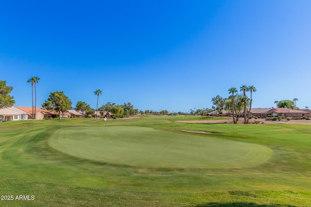 view of community featuring view of golf course and a yard