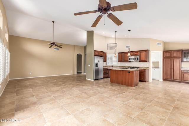 kitchen with arched walkways, a center island, stainless steel appliances, a ceiling fan, and open floor plan