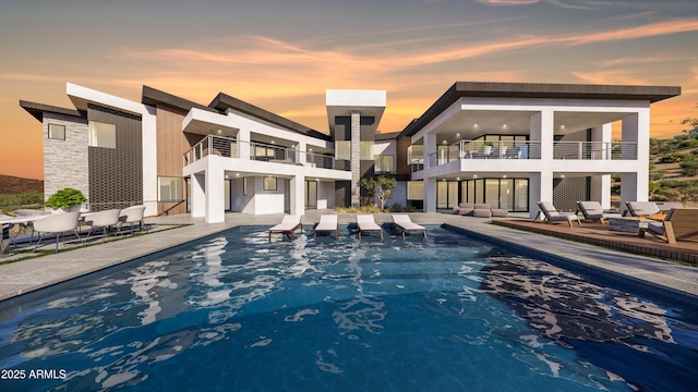 back of property at dusk featuring an outdoor pool, stucco siding, a balcony, and a patio area