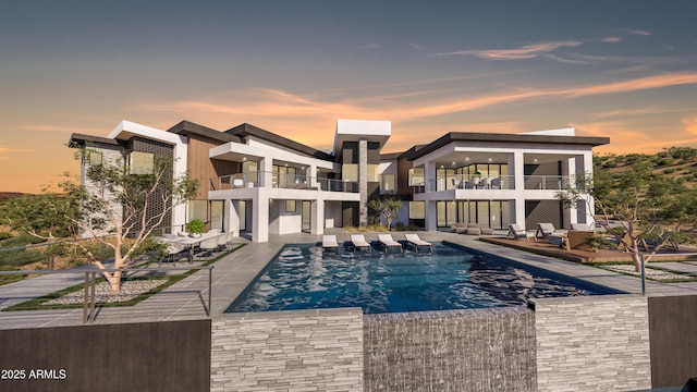 back of house at dusk with an outdoor pool, stucco siding, a balcony, and a patio area