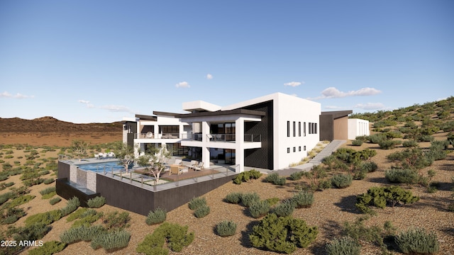 rear view of house with stucco siding, a mountain view, a balcony, and a patio