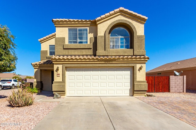 mediterranean / spanish house featuring a tile roof, stucco siding, concrete driveway, an attached garage, and fence