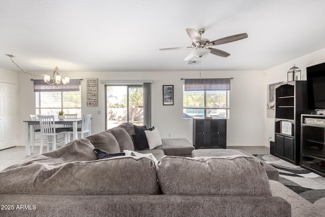 living area featuring a healthy amount of sunlight, baseboards, visible vents, and ceiling fan with notable chandelier