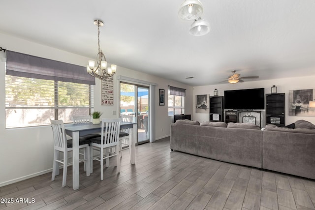 living area featuring baseboards, wood finished floors, and ceiling fan with notable chandelier