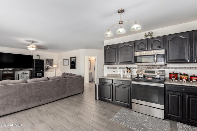 kitchen featuring appliances with stainless steel finishes, open floor plan, hanging light fixtures, light countertops, and backsplash