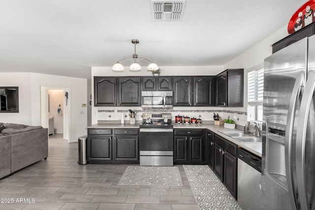 kitchen featuring light countertops, visible vents, decorative backsplash, appliances with stainless steel finishes, and a sink