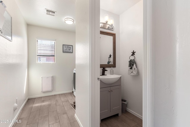 bathroom featuring wood finished floors, vanity, visible vents, and baseboards