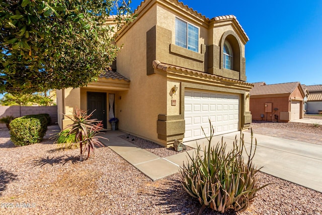 mediterranean / spanish house featuring a garage, a tiled roof, concrete driveway, and stucco siding