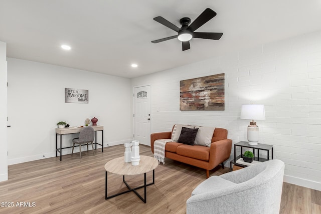 living room with ceiling fan, brick wall, and light hardwood / wood-style floors