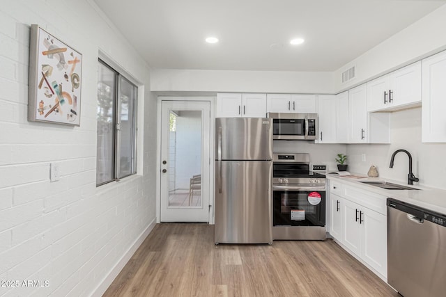 kitchen with white cabinetry, appliances with stainless steel finishes, sink, and light wood-type flooring