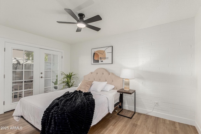 bedroom featuring french doors, wood-type flooring, a textured ceiling, and access to outside