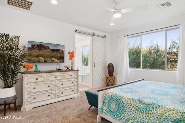 carpeted bedroom with ceiling fan, a barn door, and connected bathroom