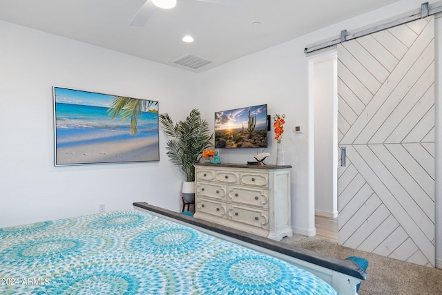 carpeted bedroom featuring a barn door and ceiling fan