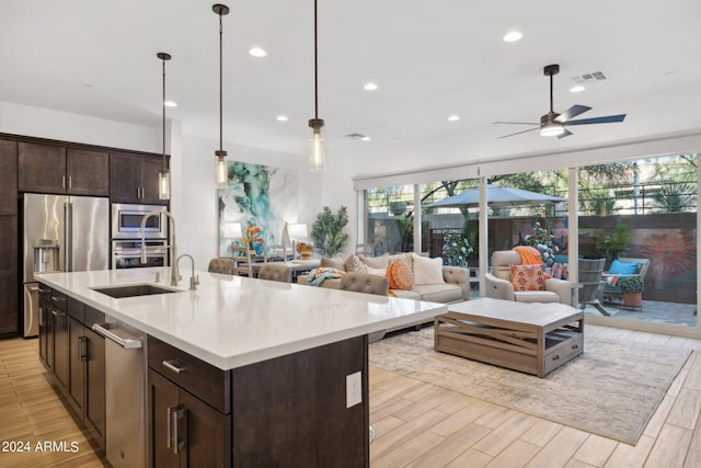 kitchen with a center island with sink, ceiling fan, hanging light fixtures, and appliances with stainless steel finishes