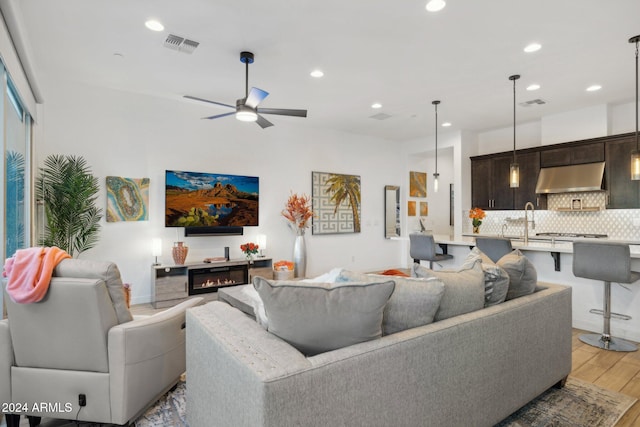 living room featuring hardwood / wood-style floors, ceiling fan, and sink