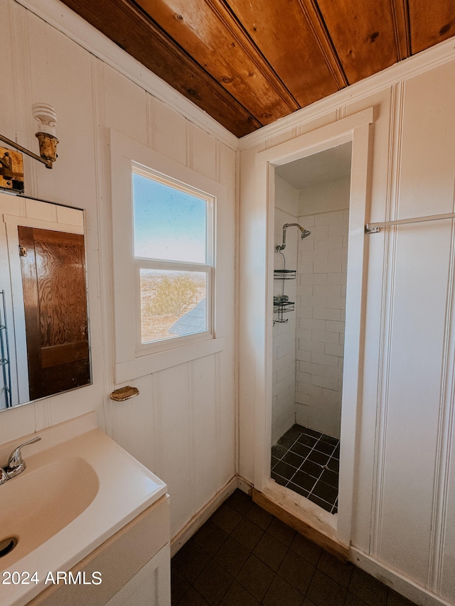 bathroom with wooden ceiling, a tile shower, and vanity