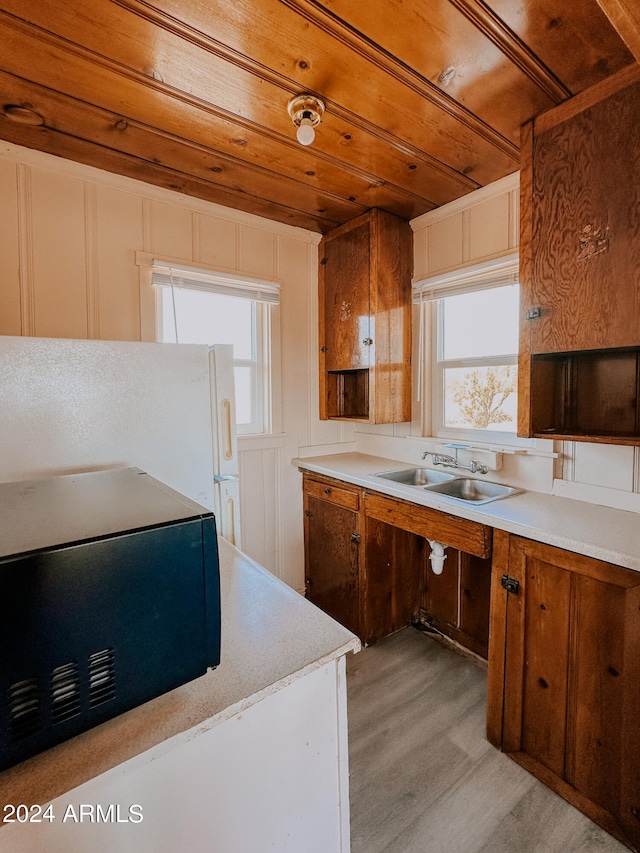 kitchen featuring light wood-type flooring, wooden ceiling, a healthy amount of sunlight, and sink