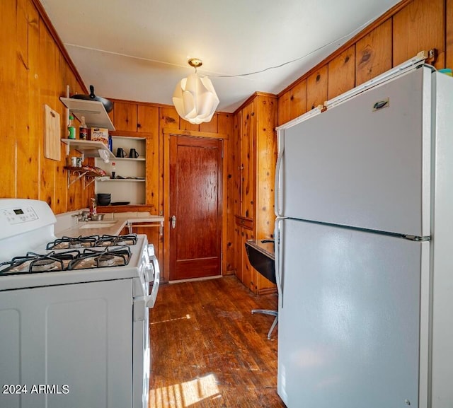 kitchen featuring dark hardwood / wood-style floors, wood walls, and white appliances