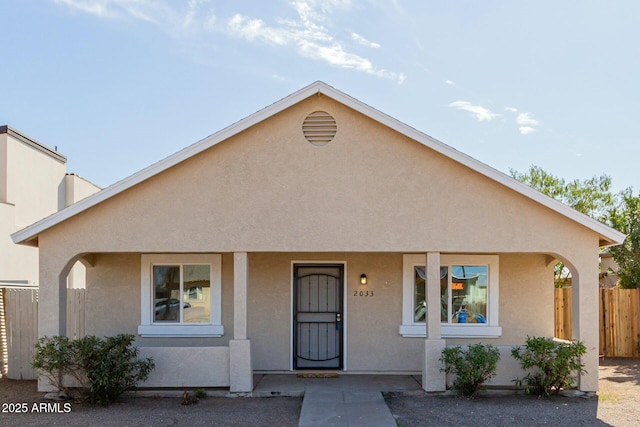 view of front of home featuring a porch, fence, and stucco siding