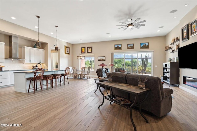 living room featuring light wood-type flooring, ceiling fan, and sink