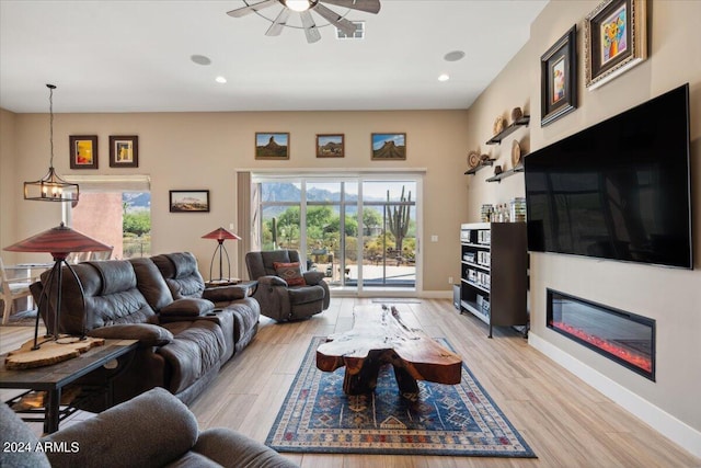 living room featuring ceiling fan with notable chandelier and light hardwood / wood-style floors