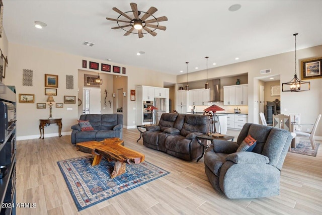 living room featuring ceiling fan with notable chandelier and light hardwood / wood-style floors