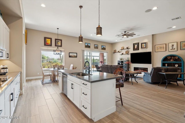 kitchen with light hardwood / wood-style floors, sink, white cabinets, hanging light fixtures, and ceiling fan