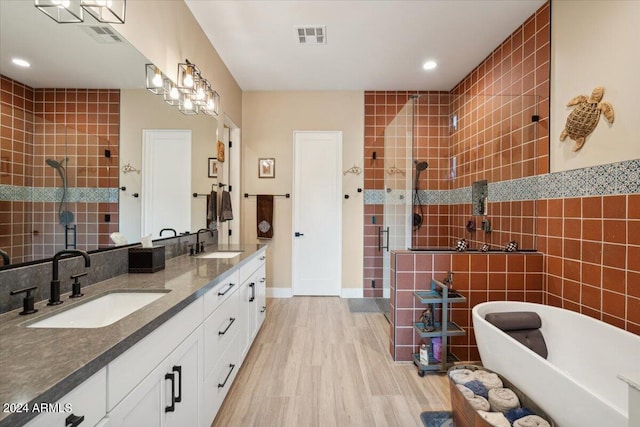 bathroom with shower with separate bathtub, tile walls, hardwood / wood-style floors, and vanity