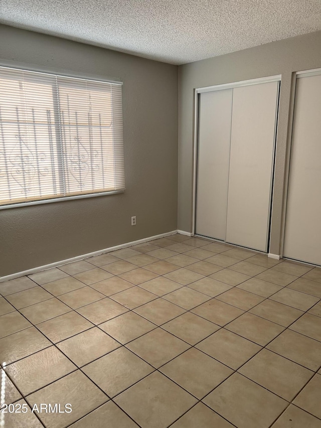 unfurnished bedroom featuring light tile patterned flooring, a textured ceiling, and a closet