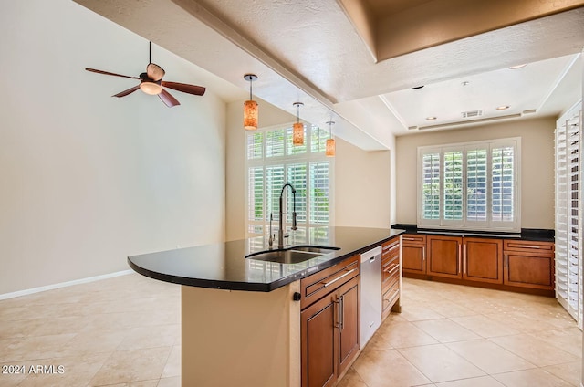 kitchen featuring light tile patterned flooring, a textured ceiling, decorative light fixtures, a center island with sink, and sink